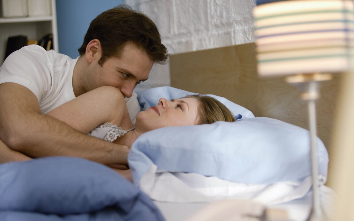 Woman in bed with a man with enlarged penis
